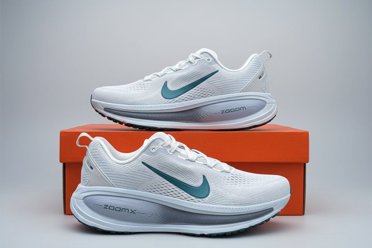 White running shoes with green accents on an orange box against a green leafy background